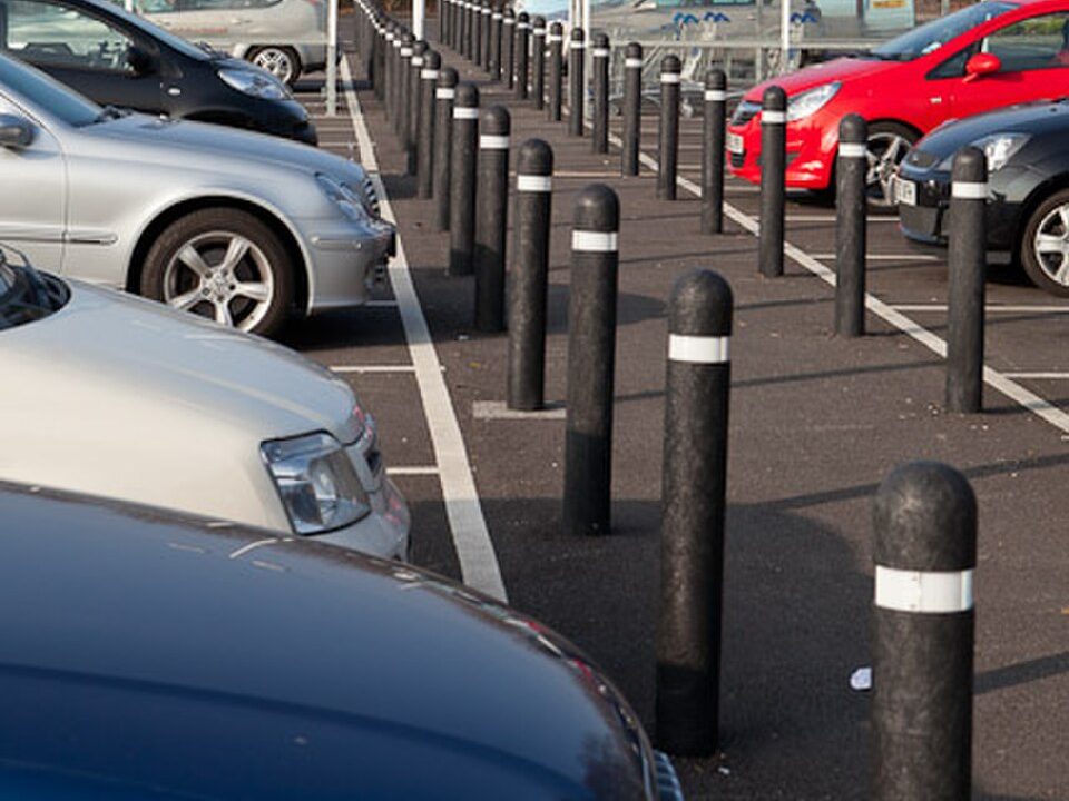 Black steel bollards with white reflective bands in a car park